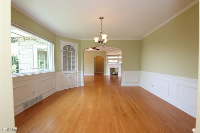 3901 Beaumont Dr, Weirton, WV 26062 - unfurnished dining area with arched walkways, light wood-style floors, a chandelier, wainscoting, and a decorative wall