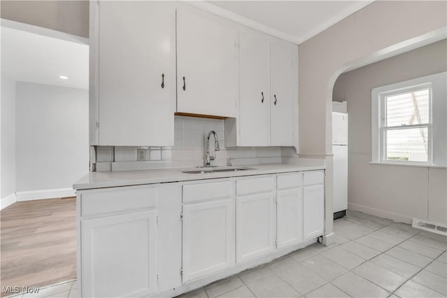 3400 W 118th St, Cleveland, OH 44111 - kitchen featuring white cabinetry, tasteful backsplash, light countertops, and arched walkways