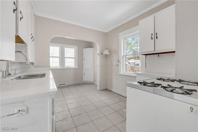 3400 W 118th St, Cleveland, OH 44111 - kitchen featuring white gas range, arched walkways, white cabinets, and light tile patterned flooring