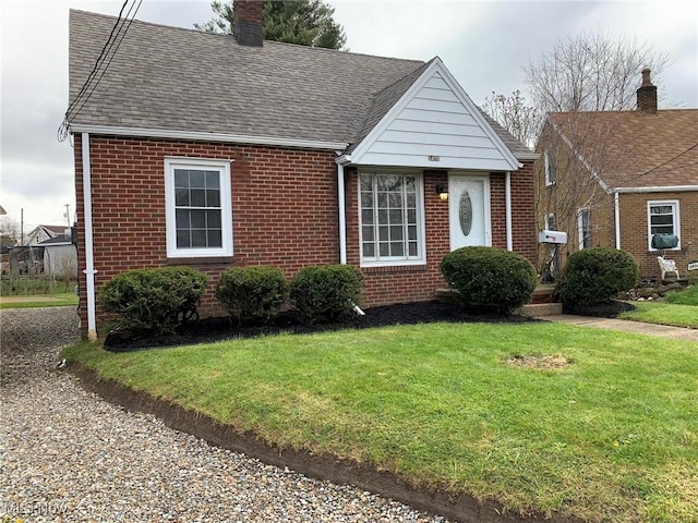 2420 Empire Rd NE, Canton, OH 44705 - view of front of home featuring brick siding, a front lawn, roof with shingles, and a chimney
