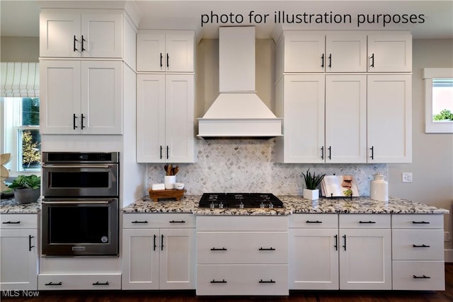 52 Boulder Blvd, Peninsula, OH 44264 - kitchen featuring custom range hood, double oven, black gas cooktop, white cabinetry, and tasteful backsplash