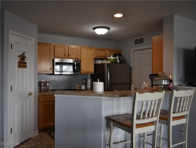 23004 Chandlers Ln Unit 4-344, Olmsted Falls, OH 44138 - kitchen with stainless steel microwave, freestanding refrigerator, a kitchen bar, a peninsula, and recessed lighting