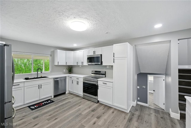 5417 Edgewood Dr, Lorain, OH 44053 - kitchen with stainless steel appliances, light wood-type flooring, white cabinetry, a textured ceiling, and light countertops