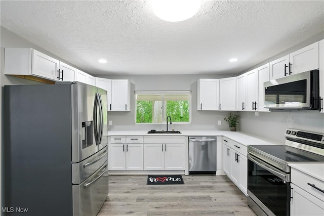 5417 Edgewood Dr, Lorain, OH 44053 - kitchen featuring appliances with stainless steel finishes, light wood-style flooring, a textured ceiling, white cabinetry, and recessed lighting