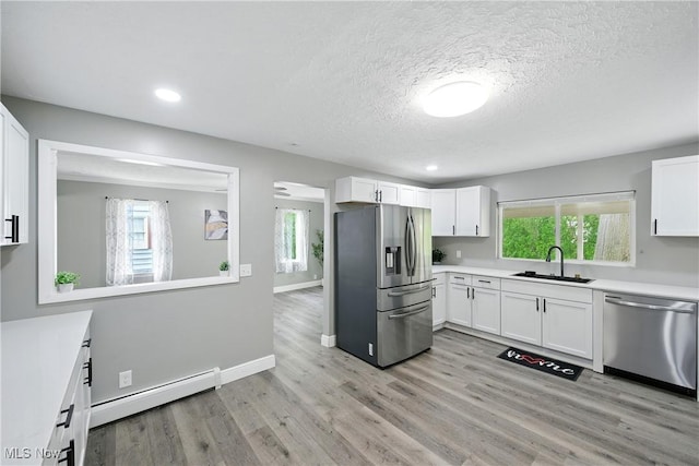 5417 Edgewood Dr, Lorain, OH 44053 - kitchen with stainless steel appliances, a baseboard radiator, white cabinetry, light countertops, and a textured ceiling