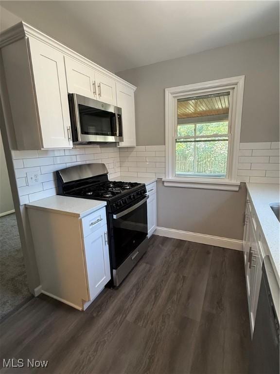 450 E 255th St, Euclid, OH 44132 - kitchen with appliances with stainless steel finishes, light countertops, dark wood-style flooring, white cabinetry, and tasteful backsplash