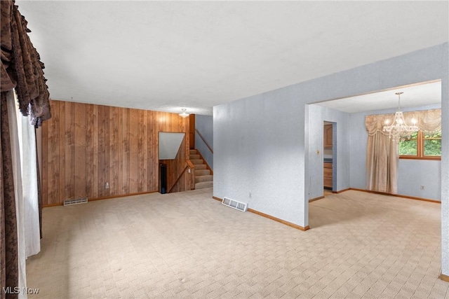 53979 Colerain Pike, Martins Ferry, OH 43935 - empty room with wooden walls, stairs, a chandelier, and light carpet