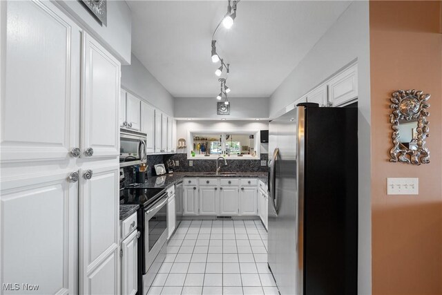 4869 Coleman Dr, Akron, OH 44319 - kitchen with appliances with stainless steel finishes, white cabinetry, light tile patterned floors, and backsplash