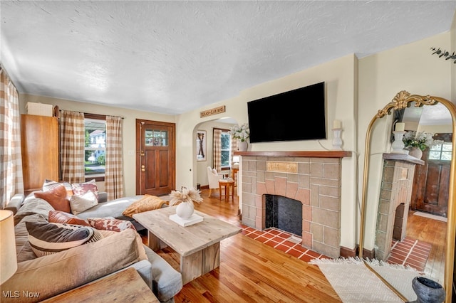 14914 Tudor Ave, Cleveland, OH 44111 - living area with a tiled fireplace, arched walkways, wood finished floors, and a textured ceiling