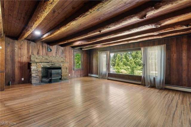 2132 Martin Rd, Mogadore, OH 44260 - unfurnished living room featuring a baseboard radiator, hardwood / wood-style flooring, a stone fireplace, wooden walls, and a wooden ceiling with exposed beams
