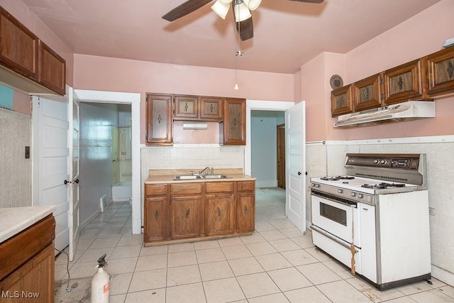 627 E 126th St, Cleveland, OH 44108 - kitchen featuring white gas stove, under cabinet range hood, a ceiling fan, light countertops, and light tile patterned flooring