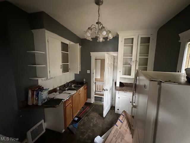 6108 Gateway Blvd S, Elyria, OH 44035 - kitchen featuring open shelves, a chandelier, dark countertops, fridge, and brown cabinets