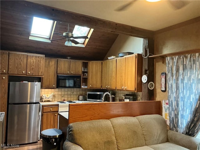 136 High St SE, Canal Fulton, OH 44614 - kitchen with stainless steel appliances, a skylight, brown cabinets, and backsplash