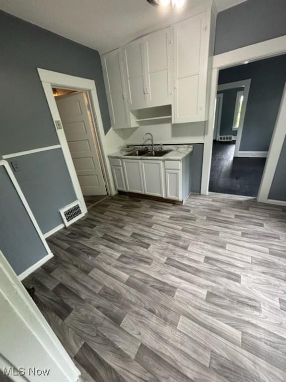 8910 Harris Ave, Cleveland, OH 44104 - kitchen with white cabinetry, wood finished floors, and light countertops