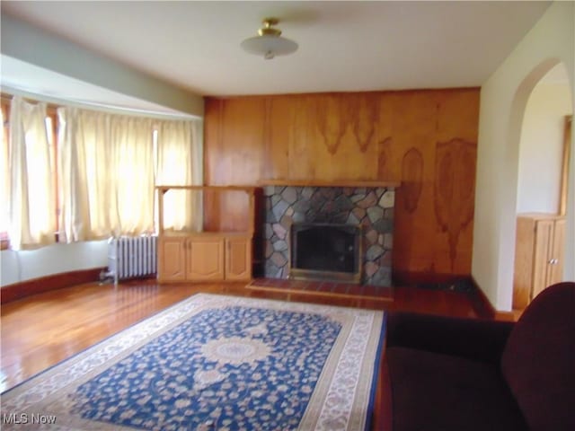 4017 N Ridge Rd W, Saybrook, OH 44004 - living room with radiator, wood finished floors, a stone fireplace, arched walkways, and wooden walls