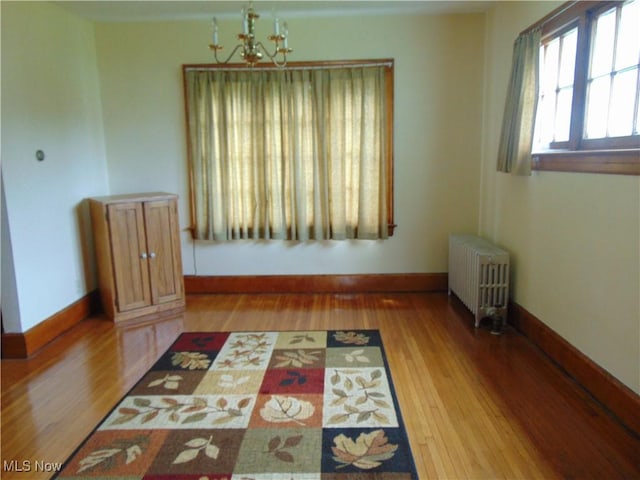 4017 N Ridge Rd W, Saybrook, OH 44004 - unfurnished dining area with radiator, wood finished floors, and a chandelier
