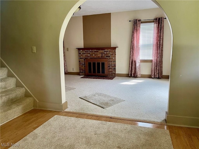 67966 Old Twenty One Rd, Cambridge, OH 43725 - unfurnished living room with arched walkways, a brick fireplace, wood finished floors, and carpet flooring