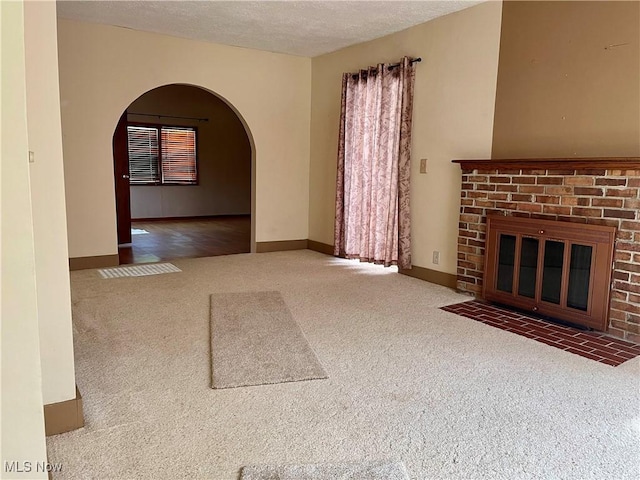 67966 Old Twenty One Rd, Cambridge, OH 43725 - unfurnished living room with arched walkways, carpet, a fireplace, and a textured ceiling