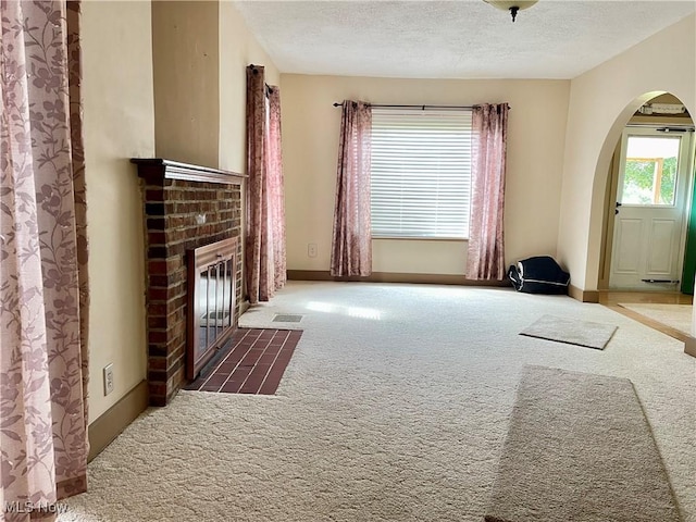 67966 Old Twenty One Rd, Cambridge, OH 43725 - unfurnished living room featuring arched walkways, carpet floors, a fireplace, and a textured ceiling