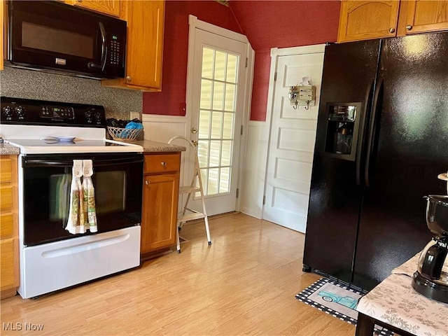 67966 Old Twenty One Rd, Cambridge, OH 43725 - kitchen featuring black appliances, light wood-style flooring, wainscoting, brown cabinets, and lofted ceiling