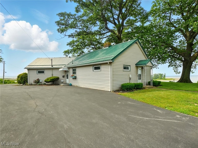 290-289 Park Ave, Conneaut, OH 44030 - view of front of home with a metal roof, a front yard, a chimney, and asphalt driveway