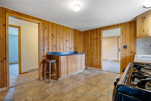 719 Pomeroy Pike, Belpre, OH 45714 - kitchen featuring black gas stove, wood walls, a textured ceiling, and light colored carpet