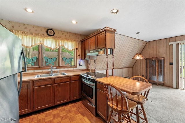 52 Arbor Rd NE, Minerva, OH 44657 - kitchen with stainless steel appliances, light countertops, brown cabinetry, under cabinet range hood, and decorative light fixtures