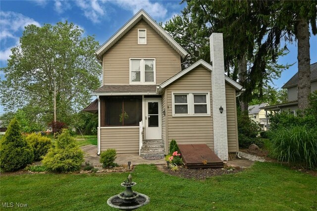 858 11th St NE, Massillon, OH 44646 - back of property with a yard, entry steps, a chimney, and a sunroom