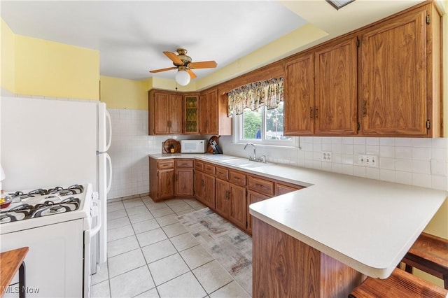 230 Hamilton Blvd, Struthers, OH 44471 - kitchen with white appliances, a peninsula, brown cabinets, a kitchen breakfast bar, and a ceiling fan