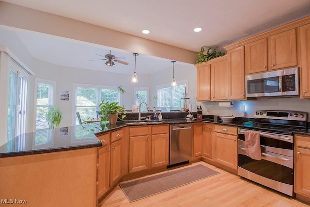 8311 Hemingway Ln, Mentor, OH 44060 - kitchen featuring stainless steel appliances, a peninsula, light wood finished floors, dark stone counters, and a ceiling fan