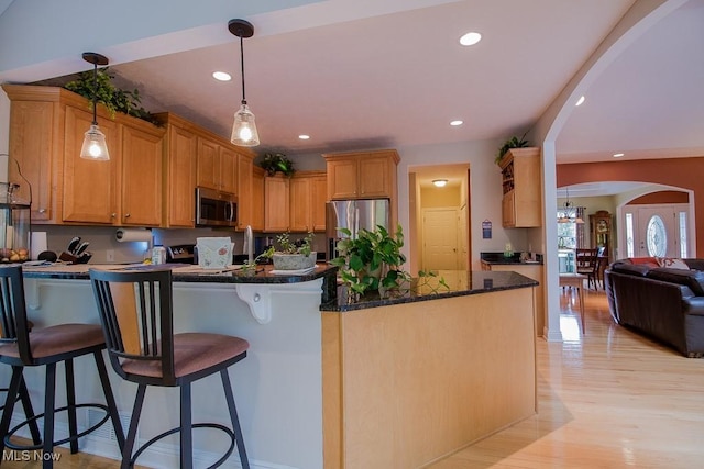 8311 Hemingway Ln, Mentor, OH 44060 - kitchen featuring appliances with stainless steel finishes, arched walkways, a peninsula, light wood-style flooring, and a breakfast bar