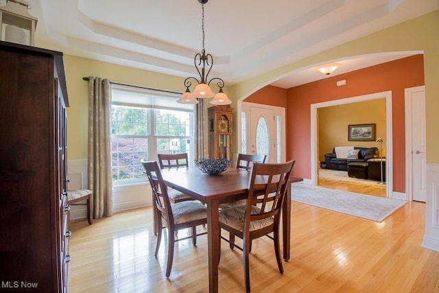 8311 Hemingway Ln, Mentor, OH 44060 - dining area featuring arched walkways, a tray ceiling, and light wood finished floors
