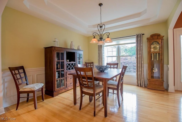 8311 Hemingway Ln, Mentor, OH 44060 - dining area featuring a raised ceiling, a chandelier, light wood-style flooring, a wainscoted wall, and a decorative wall