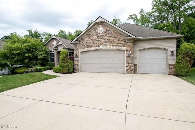 8311 Hemingway Ln, Mentor, OH 44060 - view of front of home featuring stone siding, an attached garage, concrete driveway, a front lawn, and roof with shingles