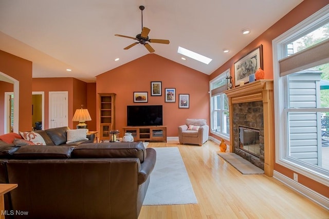 8311 Hemingway Ln, Mentor, OH 44060 - living room featuring a fireplace, light wood-style flooring, ceiling fan, vaulted ceiling, and a skylight