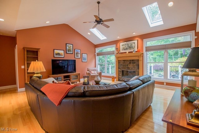 8311 Hemingway Ln, Mentor, OH 44060 - living room with a skylight, a stone fireplace, light wood-style flooring, vaulted ceiling, and plenty of natural light