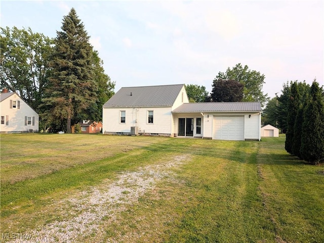 173 6th St SW, Brewster, OH 44613 - back of property with driveway, an attached garage, a metal roof, and a yard