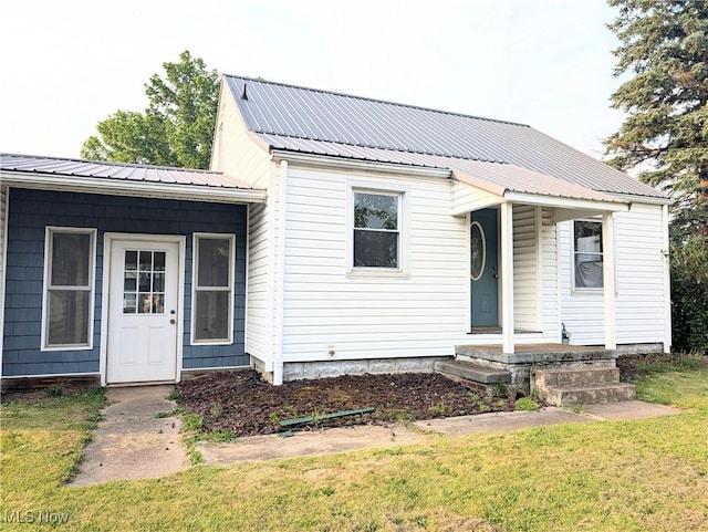 173 6th St SW, Brewster, OH 44613 - view of front of home with covered porch, a front lawn, and a metal roof