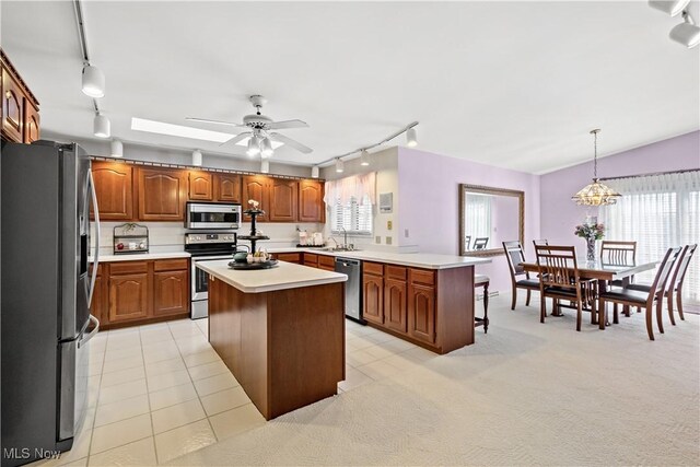 52 Hilda Cir, Bloomingdale, OH 43910 - kitchen with rail lighting, stainless steel appliances, brown cabinetry, and healthy amount of natural light