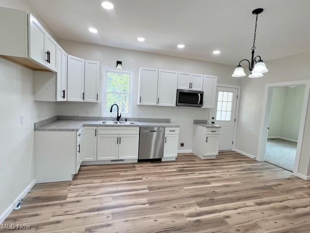619 N 3rd St, Dennison, OH 44621 - kitchen featuring appliances with stainless steel finishes, light wood-style flooring, white cabinets, a chandelier, and hanging light fixtures