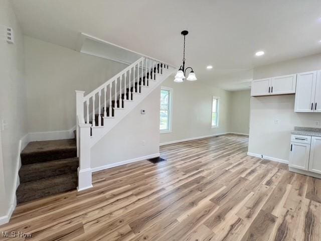619 N 3rd St, Dennison, OH 44621 - unfurnished living room with stairway, light wood-style floors, a chandelier, and recessed lighting