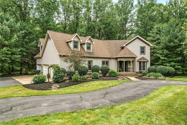 1681 State Rd, Warren, OH 44481 - view of front of home with an attached garage, asphalt driveway, a front lawn, a shingled roof, and view of wooded area