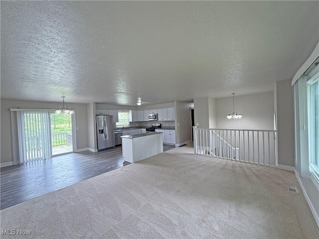 7247 Kiltie Ln, Northfield, OH 44067 - unfurnished living room with a chandelier, a textured ceiling, and light colored carpet