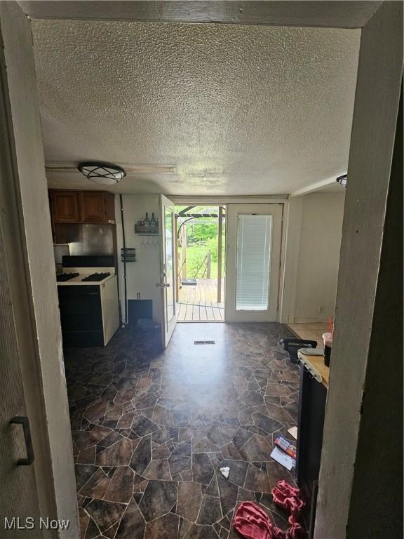 6270 Fairview Rd, Austintown, OH 44515 - kitchen with a textured ceiling, dark stone finish floors, light countertops, and brown cabinets
