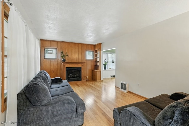 447 Allenford St, Akron, OH 44314 - living room featuring light wood-style floors, healthy amount of natural light, built in features, a fireplace, and wood walls