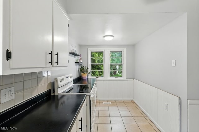 447 Allenford St, Akron, OH 44314 - kitchen with white electric range, dark countertops, a wainscoted wall, white cabinets, and decorative backsplash