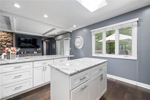 12145 The Blfs, Strongsville, OH 44136 - kitchen with dark wood-type flooring, white cabinets, a center island, light stone counters, and a skylight