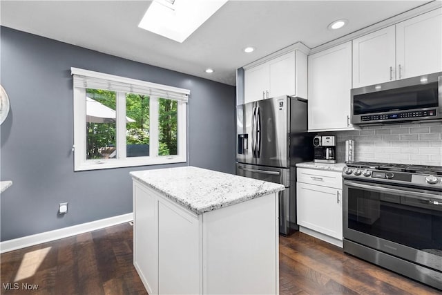 12145 The Blfs, Strongsville, OH 44136 - kitchen featuring appliances with stainless steel finishes, a skylight, white cabinets, decorative backsplash, and light stone counters