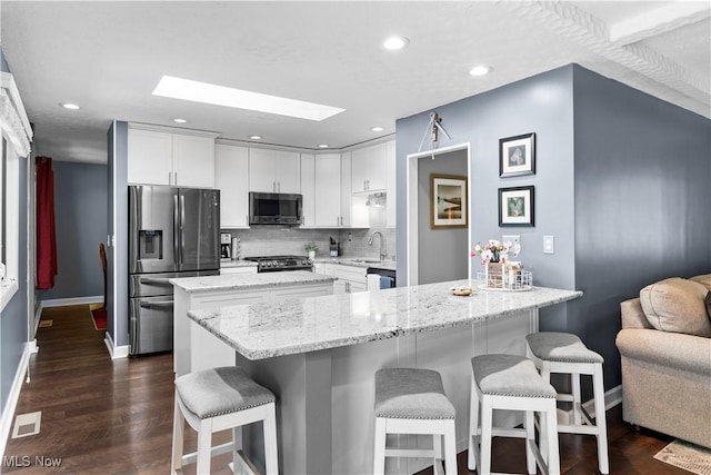 12145 The Blfs, Strongsville, OH 44136 - kitchen featuring stainless steel fridge with ice dispenser, a skylight, a kitchen bar, white cabinetry, and recessed lighting