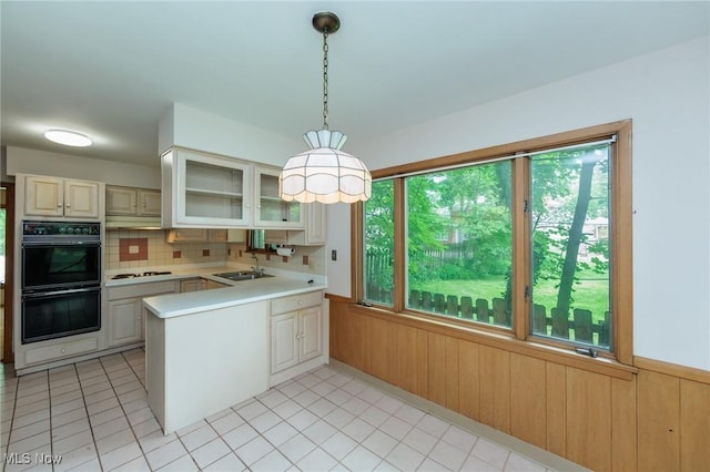 2375 Glendon Rd, University Heights, OH 44118 - kitchen featuring light countertops, a peninsula, glass insert cabinets, wooden walls, and backsplash
